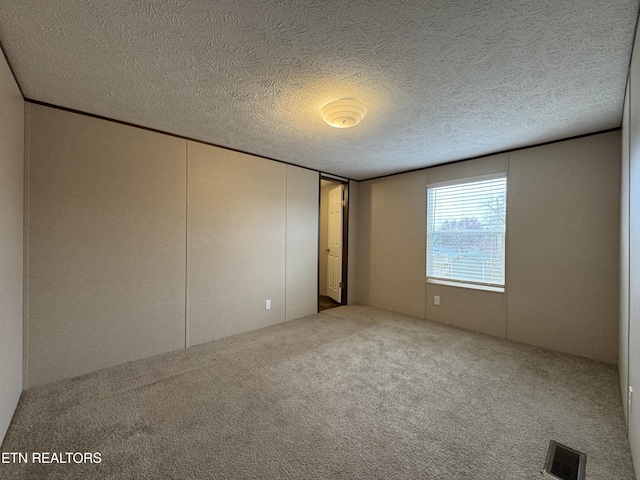 unfurnished bedroom with visible vents, a textured ceiling, and carpet floors