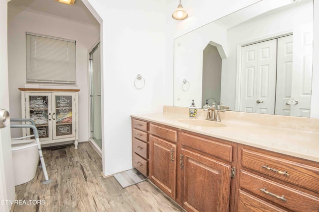 full bathroom featuring a stall shower, toilet, wood finished floors, and vanity