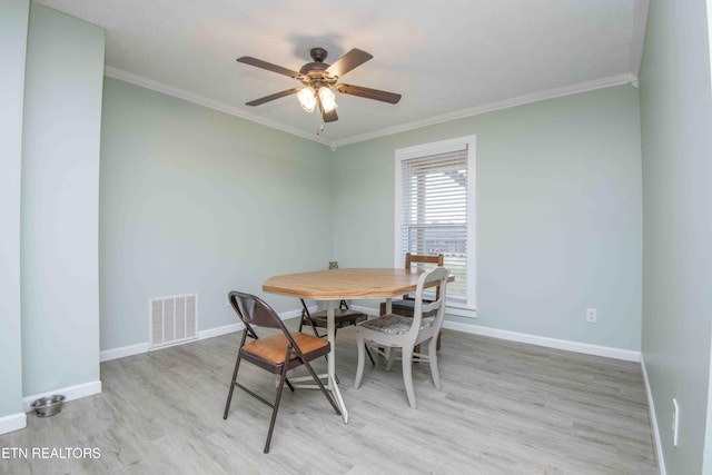 dining space with visible vents, light wood-style flooring, baseboards, and ornamental molding