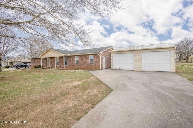 single story home featuring an outbuilding, brick siding, a detached garage, and a front lawn