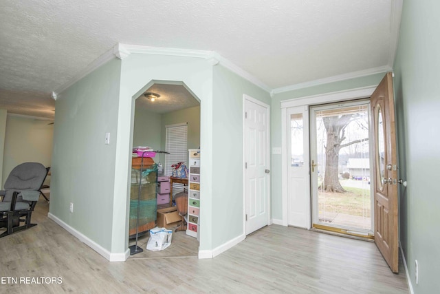 foyer featuring ornamental molding, baseboards, light wood finished floors, and a textured ceiling