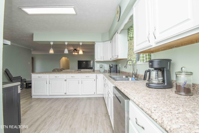 kitchen featuring a sink, a textured ceiling, stainless steel dishwasher, white cabinets, and light wood finished floors