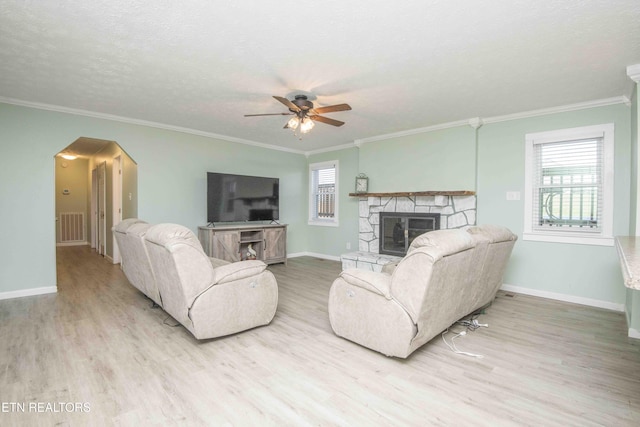 living area featuring visible vents, wood finished floors, arched walkways, a fireplace, and ceiling fan