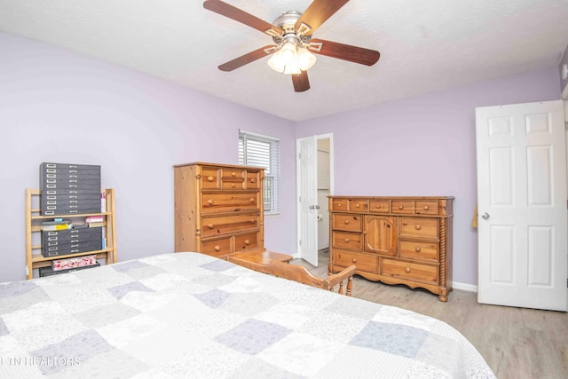 bedroom featuring a textured ceiling, wood finished floors, baseboards, and ceiling fan