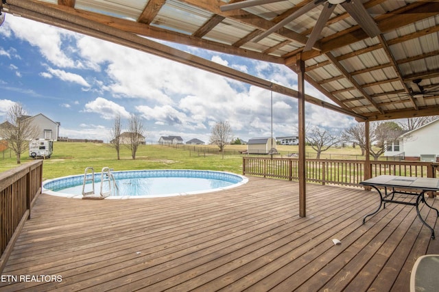 outdoor pool with a deck and a lawn