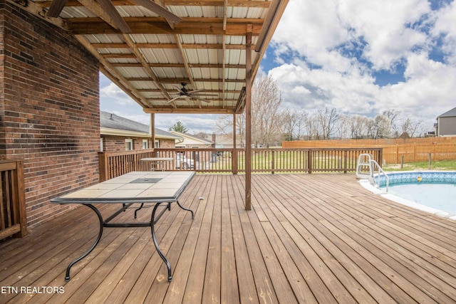 wooden terrace featuring a fenced in pool, ceiling fan, and fence