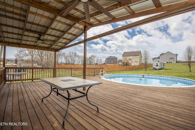 deck with a fenced in pool, a lawn, ceiling fan, and fence