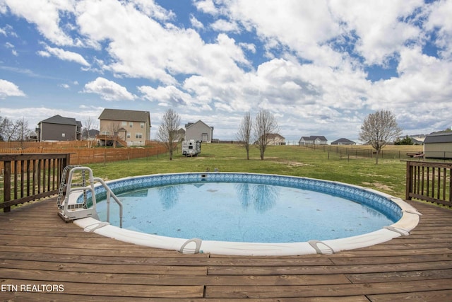 view of pool with a wooden deck, a lawn, and a fenced backyard