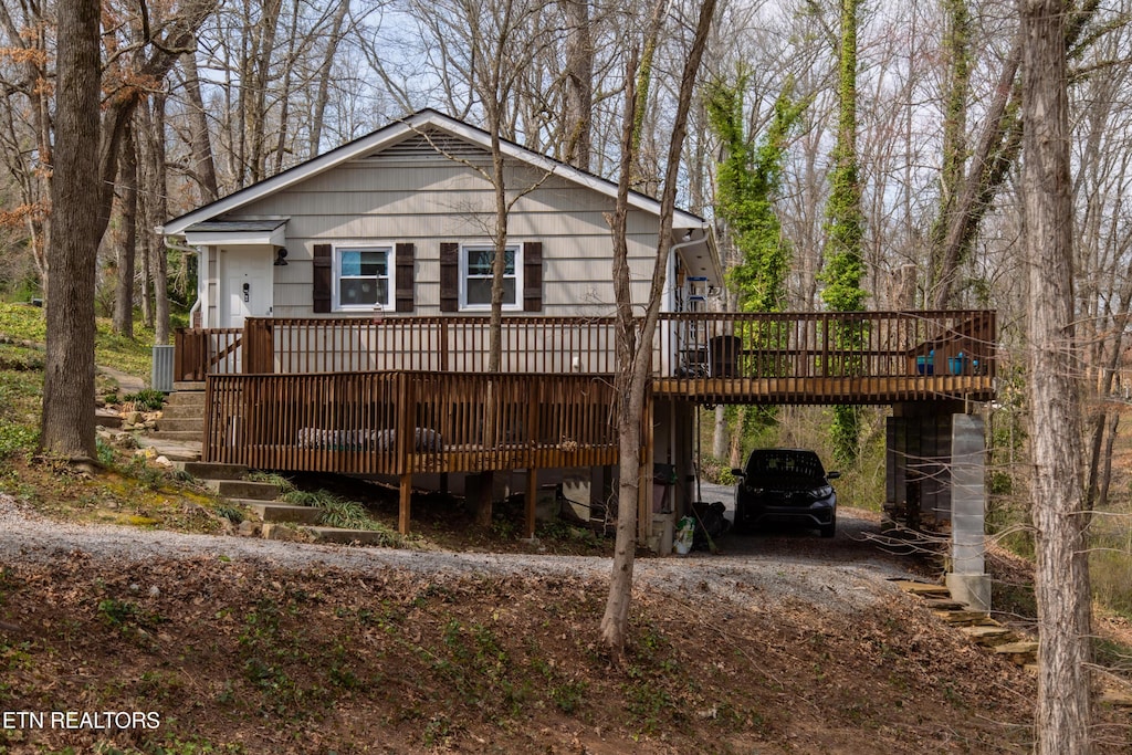 back of property featuring a carport, a deck, and driveway