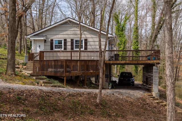 back of property featuring a carport, a deck, and driveway