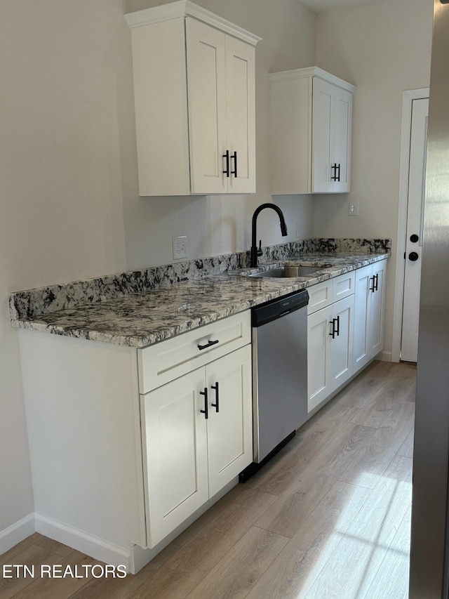 kitchen featuring stainless steel dishwasher, light stone countertops, light wood-type flooring, and a sink