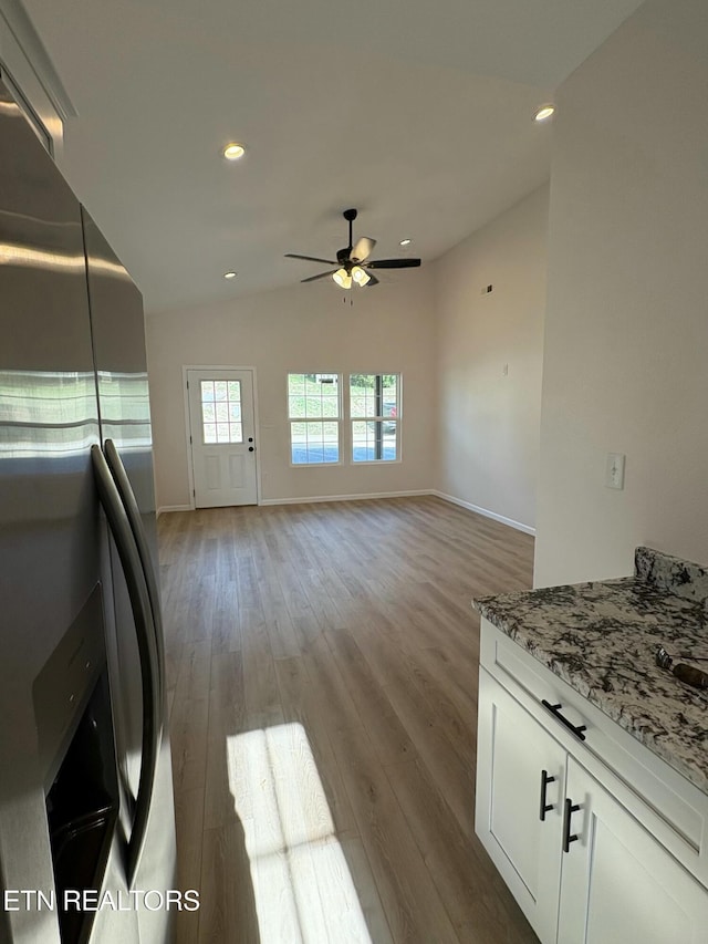 kitchen featuring light stone counters, a ceiling fan, wood finished floors, stainless steel fridge with ice dispenser, and white cabinetry