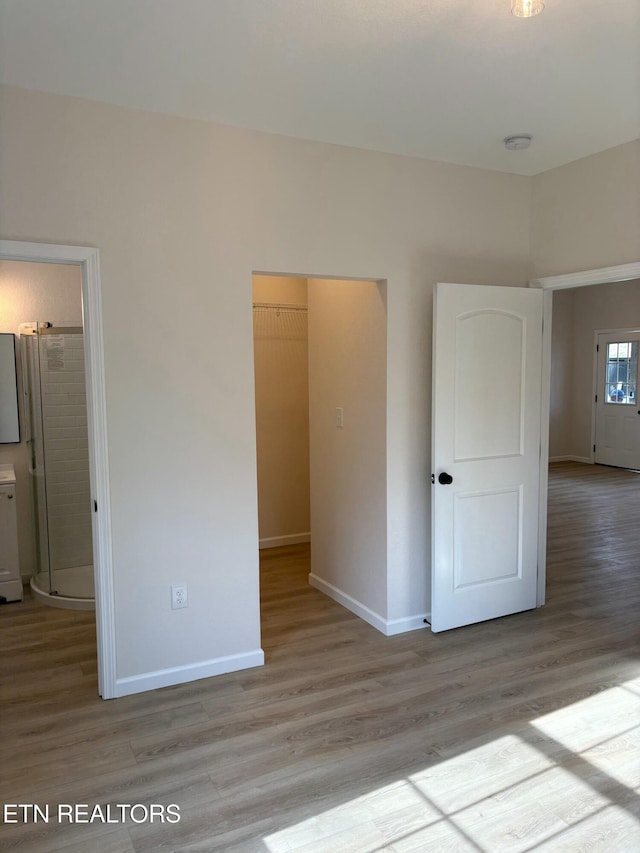 unfurnished bedroom featuring wood finished floors, baseboards, and freestanding refrigerator