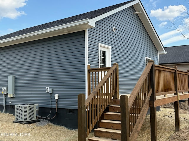 rear view of property with central air condition unit, a wooden deck, and roof with shingles