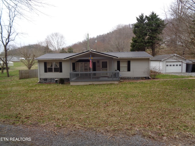 single story home featuring metal roof, a detached garage, an outbuilding, and a porch