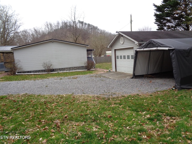 garage with gravel driveway and fence