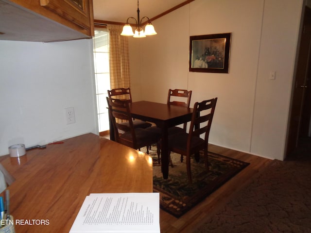 dining space with wood finished floors, a chandelier, and crown molding