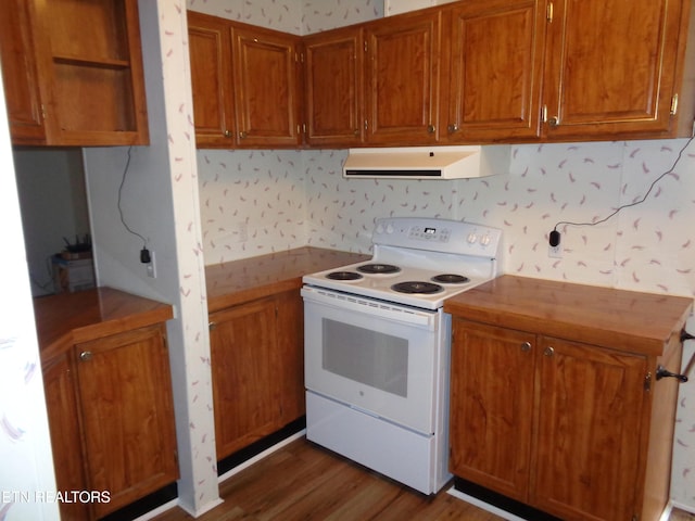 kitchen featuring wallpapered walls, range hood, brown cabinetry, and electric stove