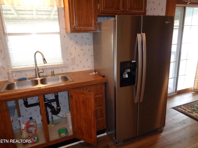 kitchen with brown cabinetry, plenty of natural light, stainless steel refrigerator with ice dispenser, and a sink