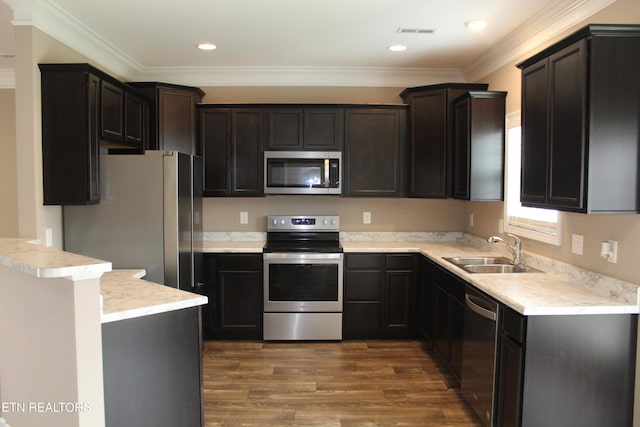 kitchen featuring visible vents, ornamental molding, wood finished floors, stainless steel appliances, and a sink