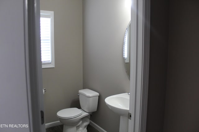 half bathroom with a sink, baseboards, and toilet