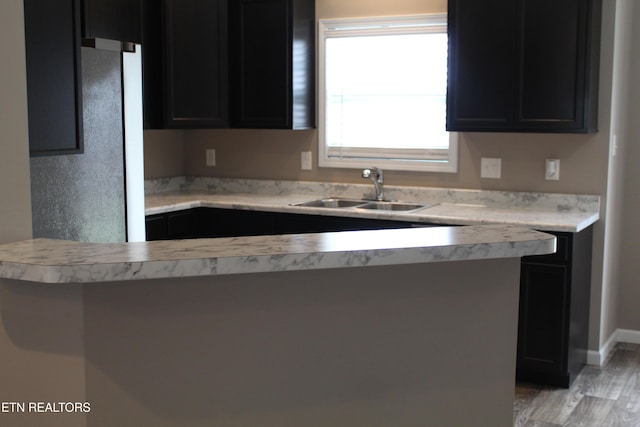 kitchen featuring light countertops, dark cabinets, and a sink