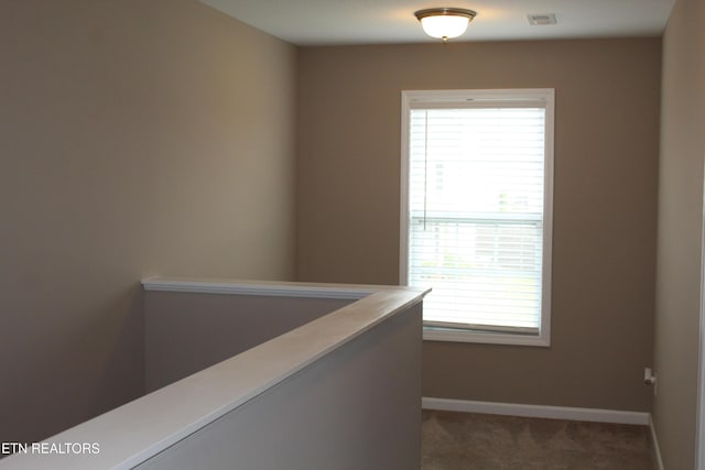 hallway with baseboards, visible vents, and carpet floors