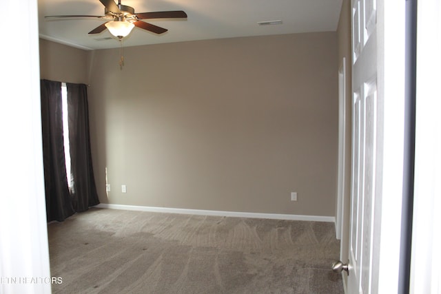 carpeted spare room featuring visible vents, baseboards, and a ceiling fan