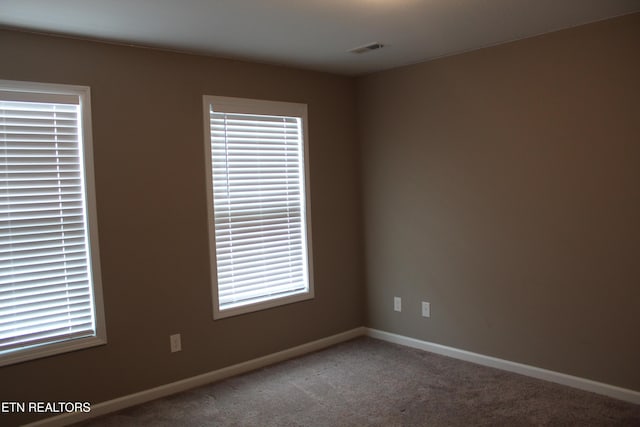 carpeted spare room with visible vents and baseboards