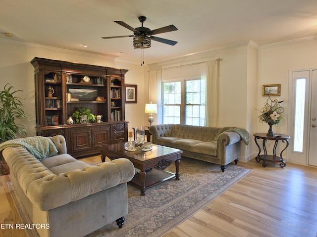 living room with crown molding, light wood-style flooring, baseboards, and ceiling fan