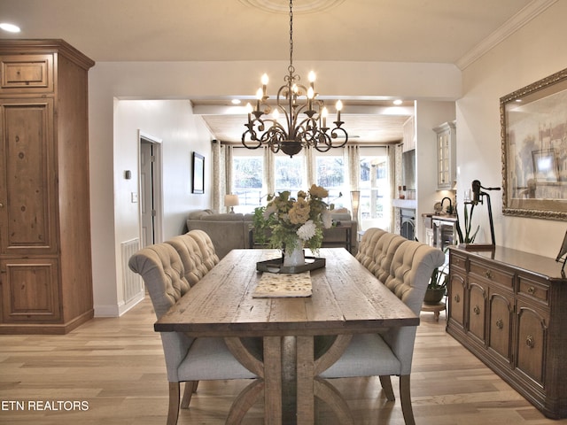 dining room featuring light wood-style flooring, baseboards, an inviting chandelier, and ornamental molding