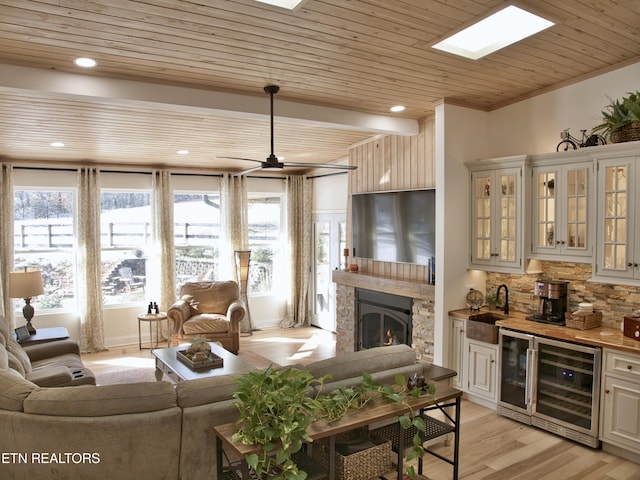 living room featuring wet bar, a healthy amount of sunlight, beverage cooler, and light wood finished floors