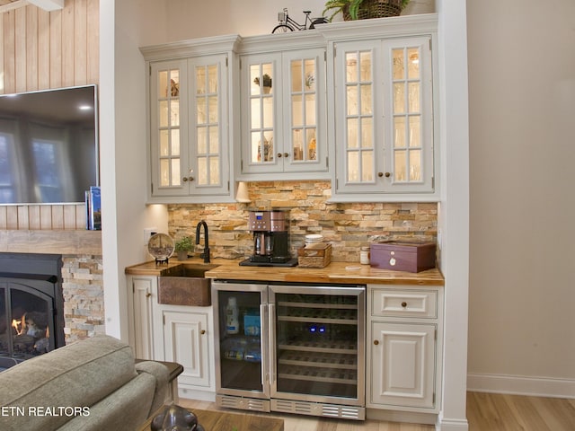 bar featuring a sink, tasteful backsplash, wine cooler, indoor wet bar, and baseboards