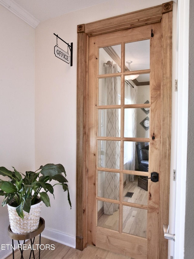 interior space featuring crown molding, baseboards, and wood finished floors