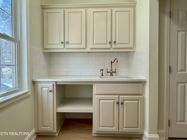 interior space with backsplash, light wood-style flooring, baseboards, and a sink