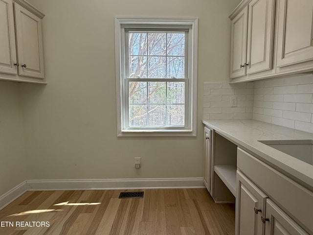 clothes washing area featuring visible vents, baseboards, and light wood-style floors