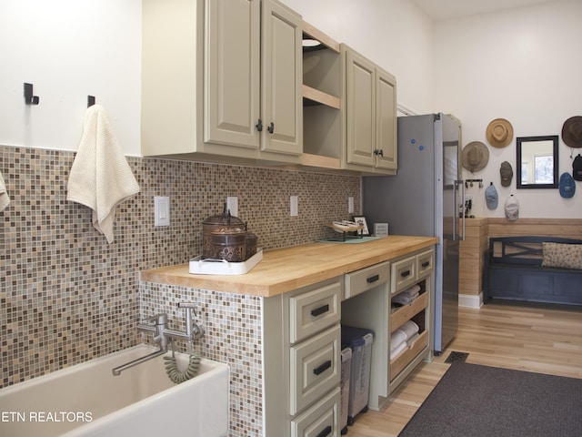 kitchen featuring light wood-type flooring, butcher block countertops, open shelves, freestanding refrigerator, and wainscoting