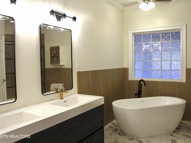 bathroom with wooden walls, a freestanding bath, wainscoting, a ceiling fan, and a sink