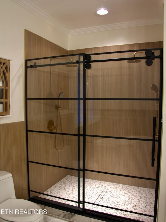 bathroom with toilet, tiled shower, and ornamental molding