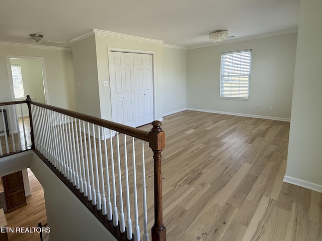 interior space with light wood-style flooring, baseboards, and ornamental molding