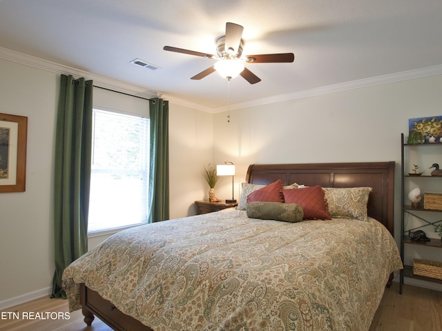 bedroom with crown molding, wood finished floors, visible vents, and baseboards