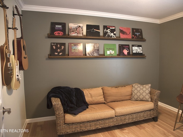 living area featuring baseboards, wood finished floors, and crown molding