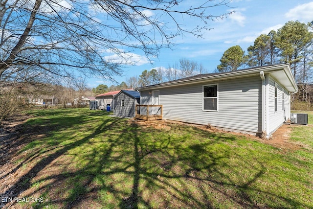 back of property featuring an outbuilding, a yard, a shed, and central AC