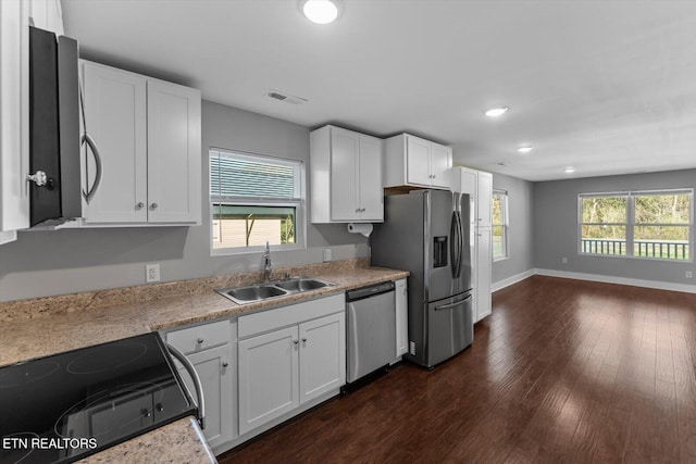 kitchen with a sink, light countertops, stainless steel appliances, white cabinetry, and dark wood-style flooring