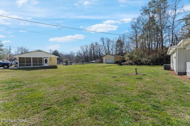 view of yard with central AC, a garage, and a sunroom