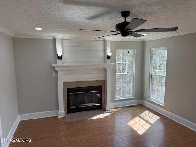 unfurnished living room with visible vents, a ceiling fan, wood finished floors, a fireplace, and crown molding