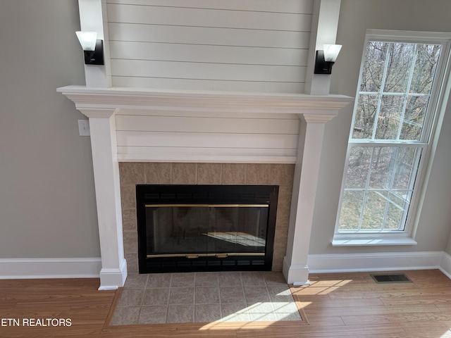 details with wood finished floors, a fireplace, visible vents, and baseboards