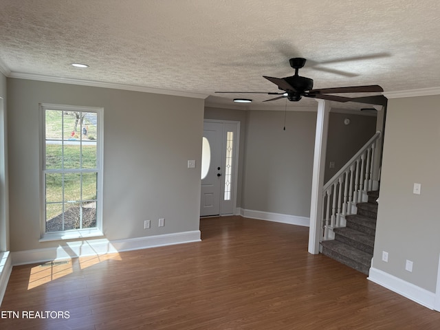 unfurnished living room featuring wood finished floors, a ceiling fan, baseboards, ornamental molding, and stairs