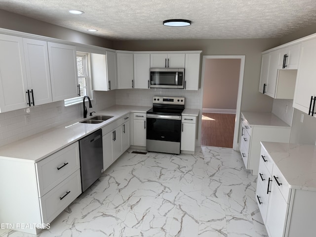 kitchen with backsplash, marble finish floor, appliances with stainless steel finishes, and a sink