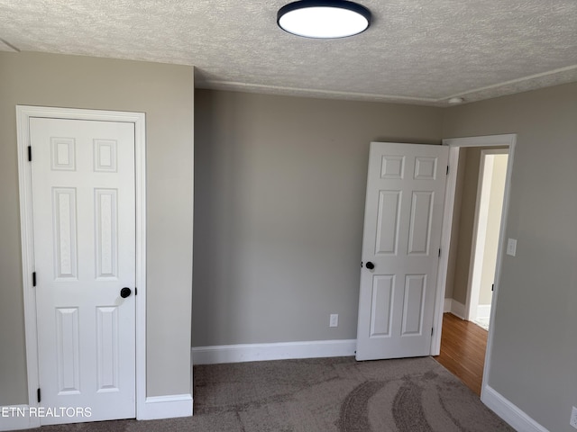 unfurnished bedroom featuring baseboards, a textured ceiling, and carpet floors